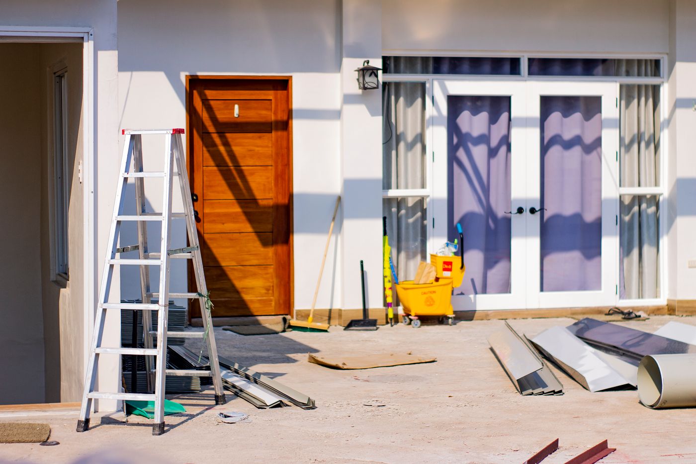 A home exterior mid-renovation with a stepladder and materials on site